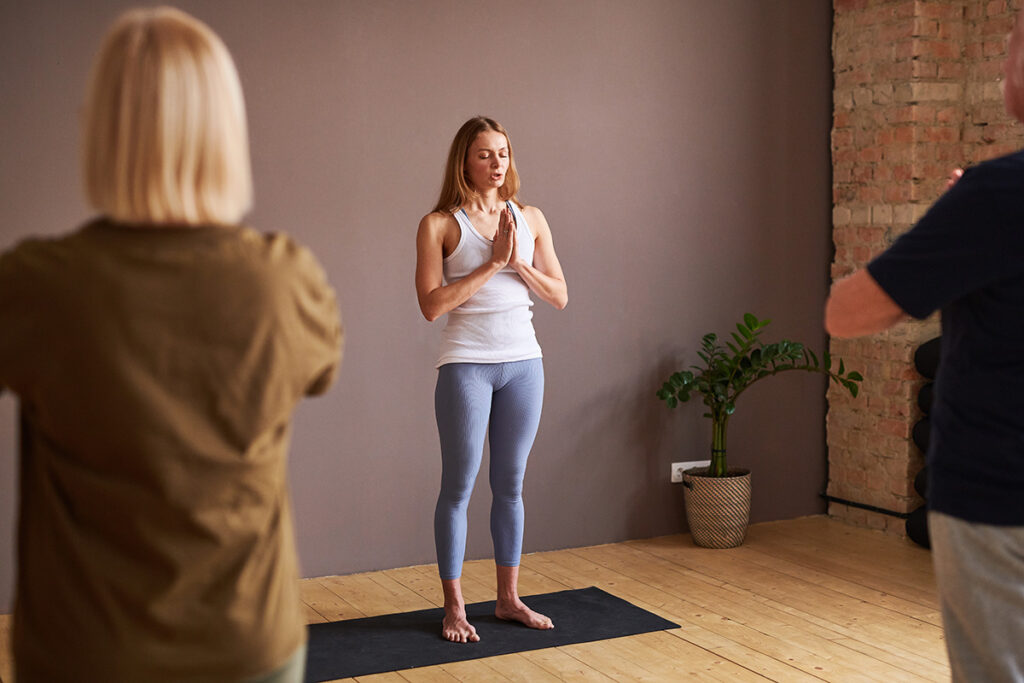 Das Bild zeigt eine Frau die einen Yoga-Kurs gibt