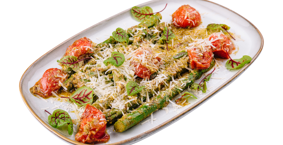 Das Foto zeigt eine Platte mit gebackenem grünem Spargel, Tomaten und Parmesan