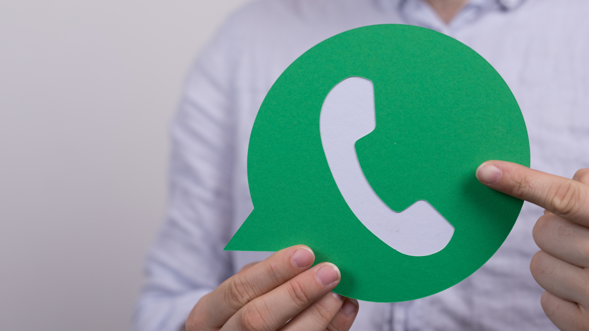 Ein Mann zeigt mit dem Zeigefinger auf das WhatsApp-Icon
