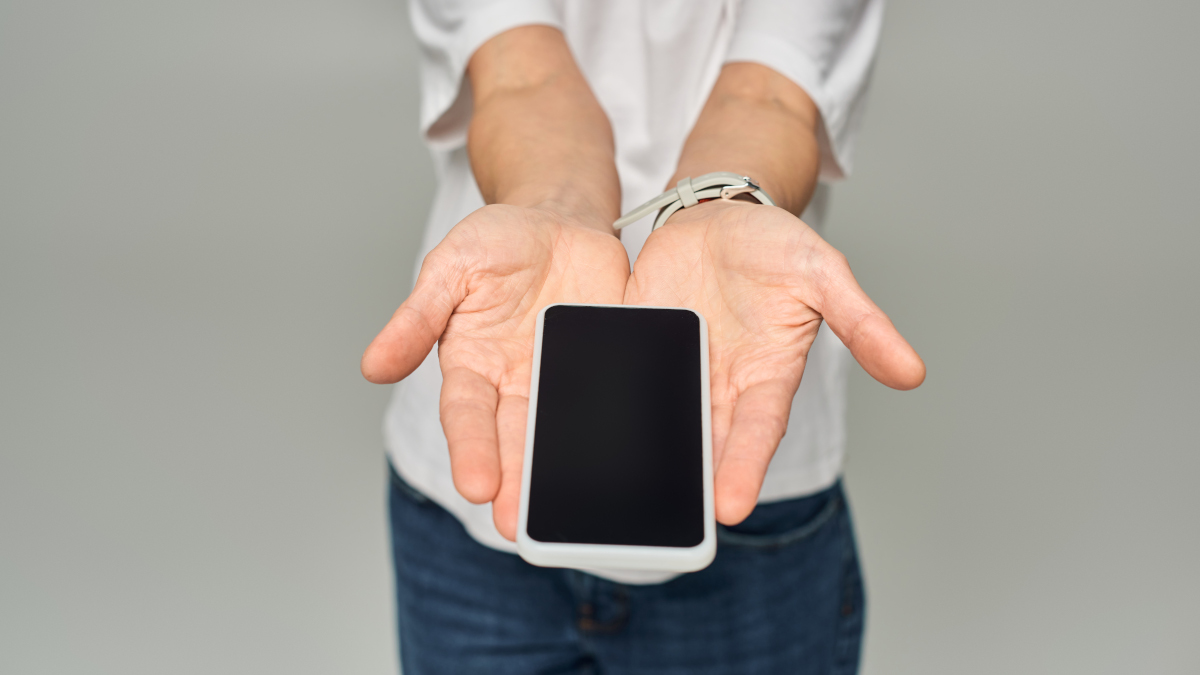 Ein altes Handy auf zwei Handflächen liegend wird in die KAmera gehalten