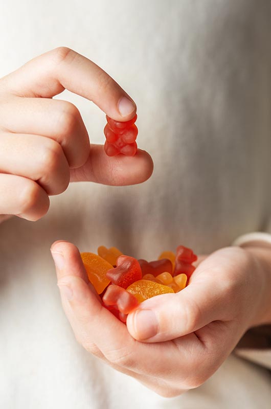 Ein Kind hält Gummibärchen in die Kamera, Detailaufnahme