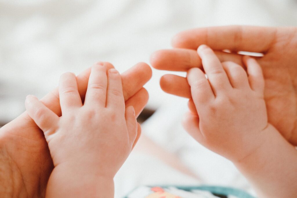 Die Hände eines Babys liegen in den Händen eines Erwachsenen