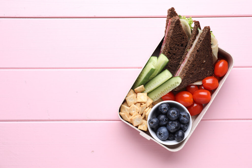 Eine Brotdose mit gesundem Inhalt auf einem rosafarbenen Tisch